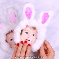 a woman holding up a baby's face with bunny ears on it