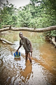 a man is standing in the water with a ball