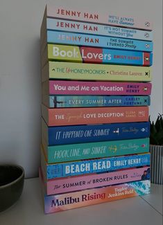 a stack of books sitting on top of a table next to a potted plant