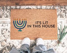 someone standing in front of a door mat that says it's lit in this house