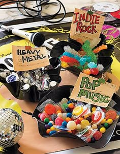 various candies are arranged in black bowls on a table with disco balls and other decorations