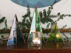 three candles are sitting on a table next to christmas trees