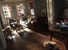 a living room filled with furniture and lots of books on top of a hard wood floor