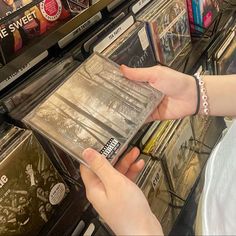 a person is selecting cds from a shelf in a store with other records on the shelves