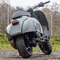 a black motorcycle parked on top of a gravel road next to a fence and green grass