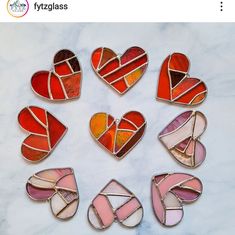 six heart shaped stained glass pieces arranged in a circle on a white marble table top