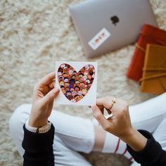 a person holding up a heart shaped sticker