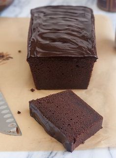 a piece of chocolate cake sitting on top of a cutting board next to a knife