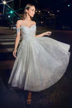 a woman in a white dress is walking down the street at night with her hand on her hip