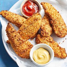 fried chicken sticks with mustard and ketchup on a white plate next to dipping sauce