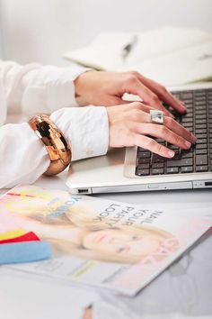 a woman is typing on her laptop while sitting at a desk with other office supplies