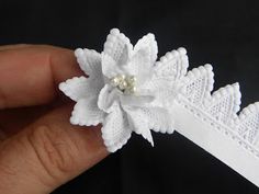 a hand holding a white flower on top of a headband