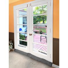 an open door leading to a deck with chairs and table in the room behind it