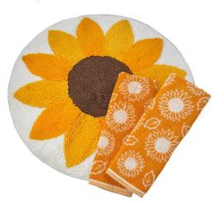 a sunflower rug and two orange towels on a white plate