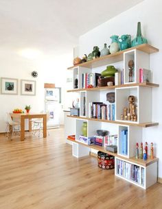 a living room filled with lots of furniture and bookshelves on top of wooden floors