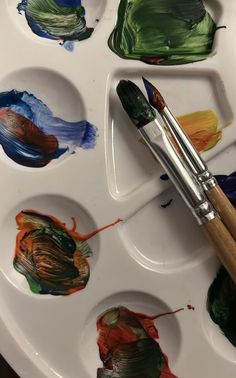 an artist's palette with paint and brushes on it