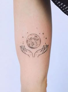 a woman's arm with two hands holding the moon