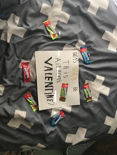 a sign that is laying on top of a bed with candy bars all over it