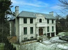 a large white house sitting in the middle of a snow covered yard with trees and bushes