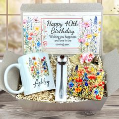 a birthday gift box with two coffee mugs and a spoon in it, sitting on a table