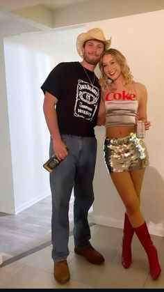 a man standing next to a woman wearing short shorts and cowboy boots in front of a white wall