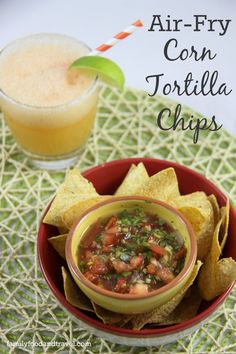 a bowl filled with tortilla chips next to a drink