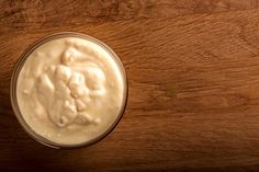 a glass filled with cream sitting on top of a wooden table