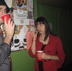 a man talking on a cell phone next to a woman holding a red cup in her hand