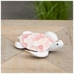 a small white and pink turtle sitting on top of a wooden table