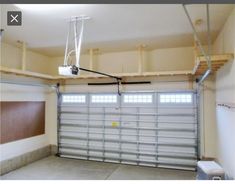 an empty garage with a basketball hoop hanging from the ceiling and overhead lighting above it