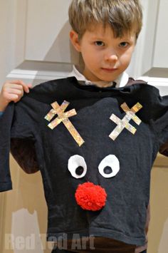 a young boy holding up a black shirt with crosses on it