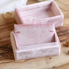 two pink jewelry boxes sitting on top of a wooden table next to gold nuggets