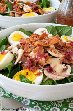 two white bowls filled with bacon, hard boiled eggs and spinach on a table