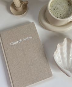 a book sitting on top of a white table next to a cup and saucer