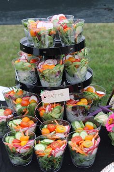 a table topped with lots of salads and cups filled with vegtables