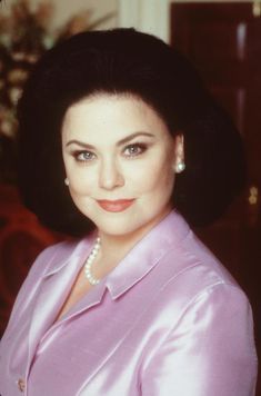 a woman in a pink suit and pearl necklace