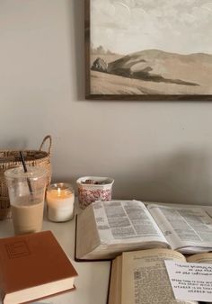 an open book sitting on top of a table next to a cup of coffee and candle