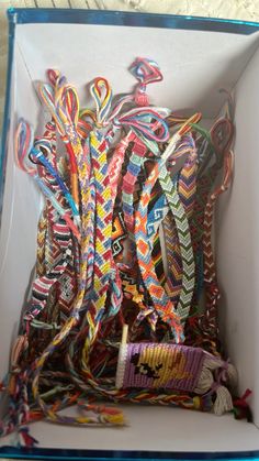 an open box filled with lots of different colored bracelets and hair ties on top of each other