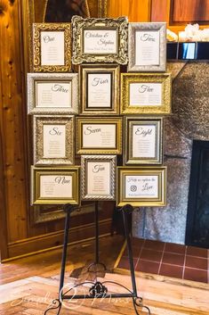 a table with many frames and place cards on it in front of a fire place