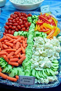 an assortment of vegetables are displayed on a platter at a buffet table with other food items