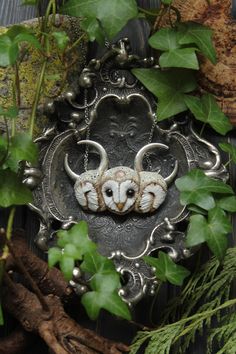 an animal head is hanging on the side of a metal plaque with leaves around it