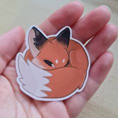 a hand holding a sticker with an image of a fox