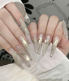 a woman's hand with long, shiny nails and gold foil on it is holding onto her white dress