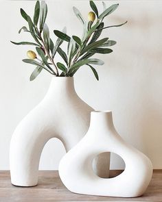 two white vases sitting on top of a wooden table