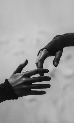 two people reaching out their hands to touch each other's hand, in black and white