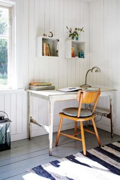 a white desk and chair in a room next to a window with open shelves on the wall