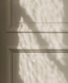 the shadow of a teddy bear is cast on a white door with a black handle