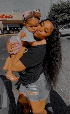 a woman holding a baby in her arms and kissing the face of another woman's head