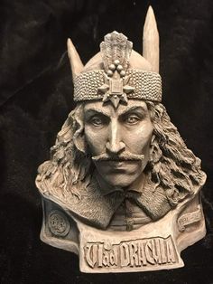 a statue of a man wearing a horned headdress and holding a sign with the word vaga dracula on it