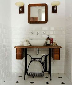 a bathroom with a sewing machine sink and mirror on the wall next to it is tiled flooring